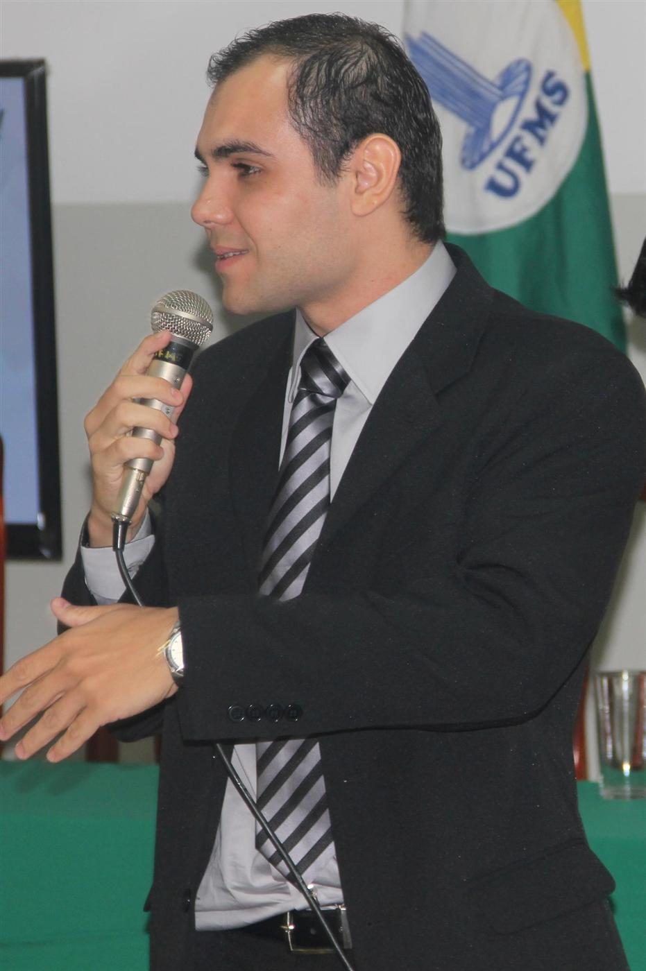Rodney Júnior de terno fala ao microfone em evento na UFMS